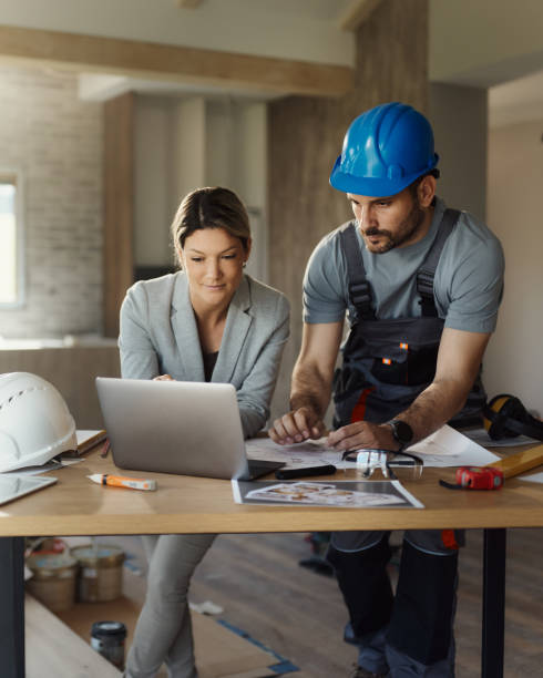 istock Female inspector and manual worker using laptop at renovating house. 1956802607