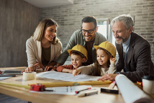 istock Happy family and their architect reading blueprints during home renovation process. 1956805222