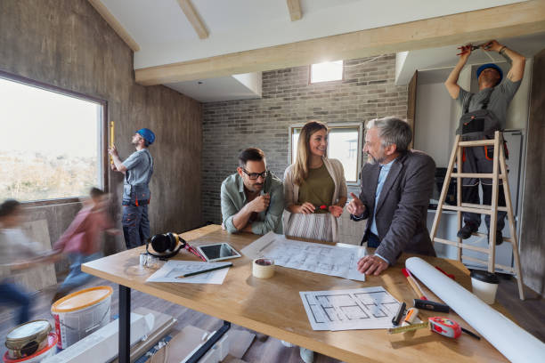 Happy parents making plans with an architect during home renovation process. Happy parents talking about blueprints with interior designer during renovation of their home. Blurred motion. renovation stock pictures, royalty-free photos & images