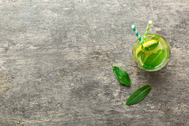 istock Caipirinha, Mojito cocktail, vodka or soda drink with lime, mint and straw on table background. Refreshing beverage with mint and lime in glass top view flat lay 1956823366