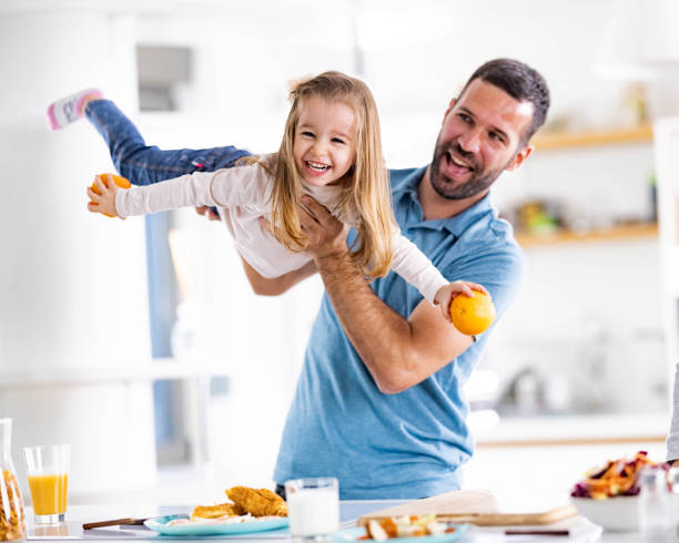 istock Cheerful single father having fun with his daughter in dining room. 1956831815