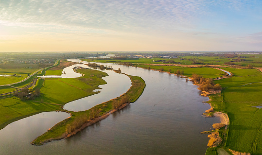 Panoramic aerial view on the river IJssel and Reevediep Bypass waterway during a springtime sunset in Overijssel. The flow of the river is leading towards Kampen city in the distance.