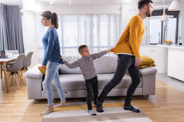 Oh no, you are not getting a divorce! Small boy pulling his parents in the living room who are about to get a divorce. arguing couple divorce family stock pictures, royalty-free photos & images