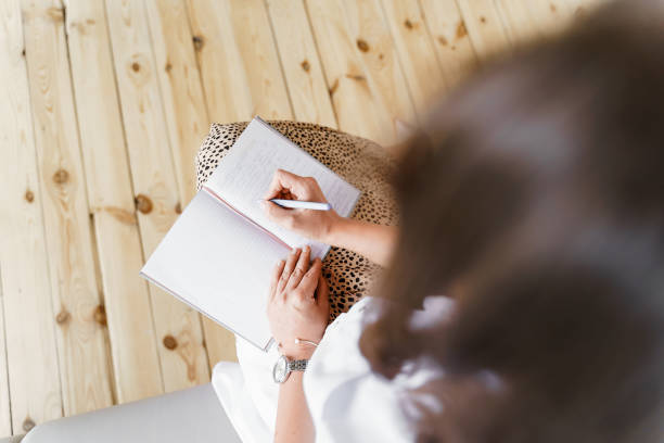 istock View from above. A woman is sitting and writing in a notebook 1956862497