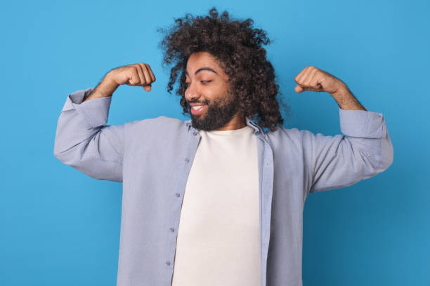 istock Young strong Arabian man takes strongman pose and shows biceps stands in studio 1956866256