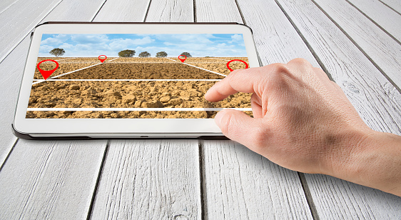 Land plot management - real estate concept with a vacant land available for building construction with a digital device