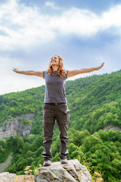 Smiling woman enjoying nature with spread arms.