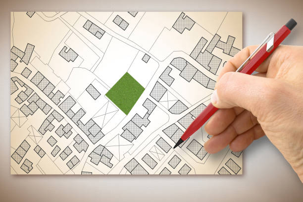 istock Engineer drawing an imaginary cadastral map of territory with buildings, fields, roads and land parcel - building activity concept 1956882879