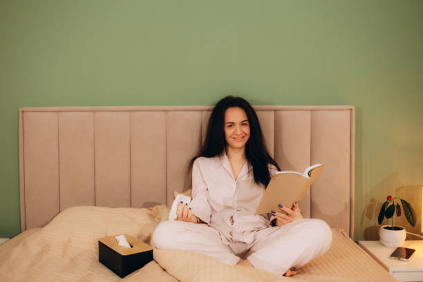 istock Happy woman reading a book in bed 1956884167