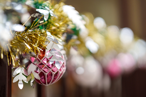 In a close-up shot, Christmas ornaments are beautifully decorated on a metal fence grill, creating a festive and charming holiday scene.