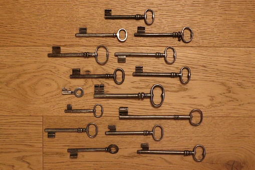 antique keys of different shapes of old doors arranged on wooden floor