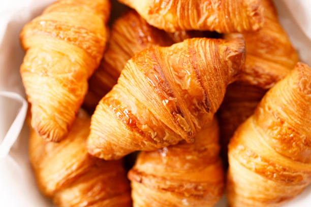 Fresh baked croissants on white table. Closeup.
