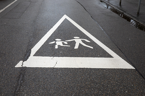 Caution: Children Playing - Urban Street Safety Sign on Wet Pavement.