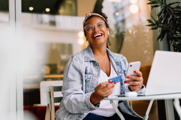 mujer joven usando un teléfono inteligente para compras en línea en una cafetería - comprar fotografías e imágenes de stock