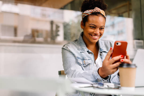 istock Cheerful woman using a phone during her coffee break at a coffee shop 1956924768