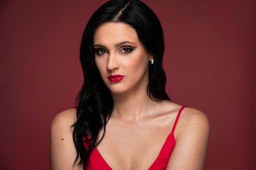 Beauty studio portrait of young beautiful woman against red background