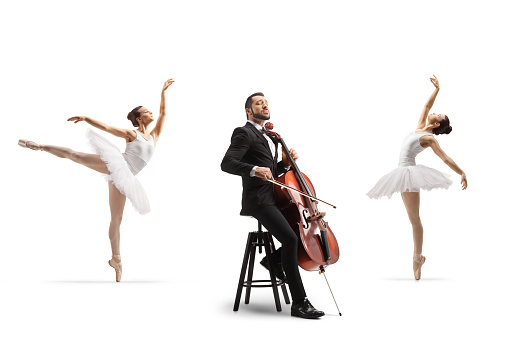 Ballerinas dancing and a male musician in a sitting on a chair and playing a cello isolated on white background