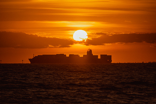 A scenic view of a ship in the sea at sunset