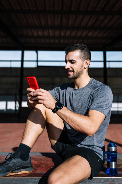 istock Fit man using smartphone relax resting from exercise in a bench outside. Active sports athlete texting with phone during training. 1956959086