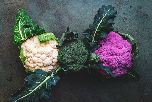 White and lilac cauliflower, broccoli cabbage from farm market on old rustic green table