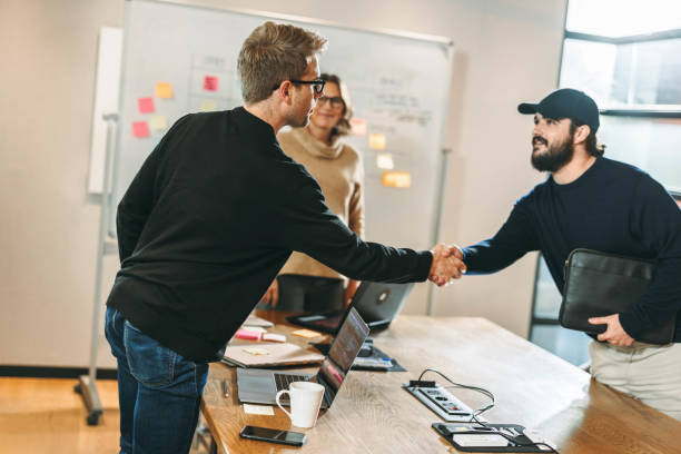 istock Successful partnership: Business men shaking hands in a creative tech company 1956988439