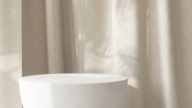 istock Close up modern rock stone white side table podium in sunlight, leaf shadow on beige brown curtain 1957008955