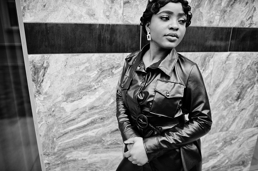 Fashionable beautiful african american woman posing in black leather jacket at street. Earring in the nose.