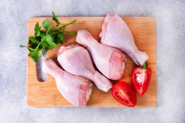 istock Raw chicken drumstick on a cutting board. Chicken meat for cooking. top view. 1957044358