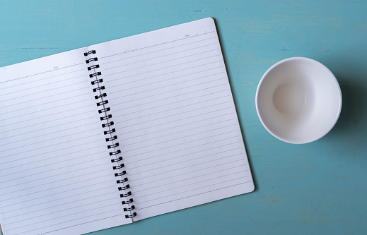 Plain notebook and white cup