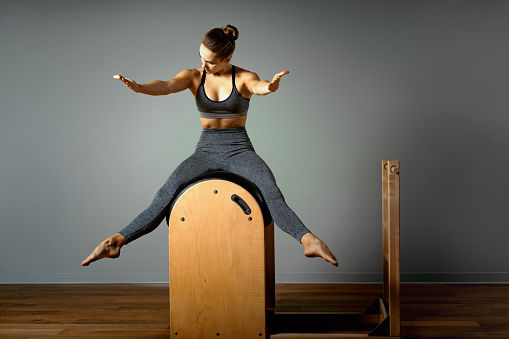 Pilates, fitness, sport, training and people concept - woman doing exercises on a small barrel. Correction of impellent apparatus, correct posture