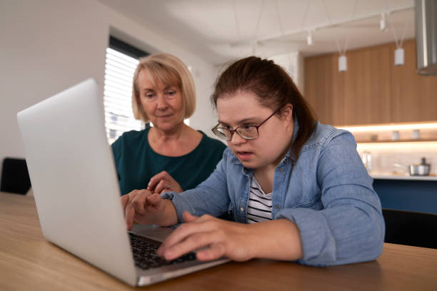 istock Down syndrome woman using computer with help of her mother 1957074517