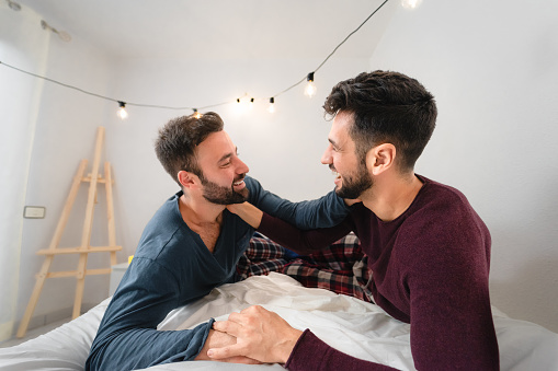 Happy gay couple having tender moments in bedroom - Homosexual love relationship and gender equality concept