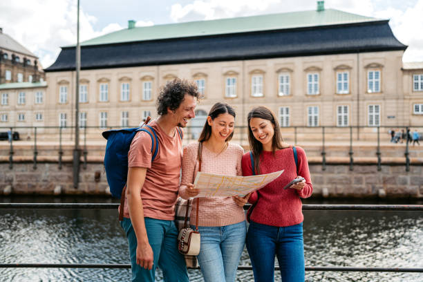 istock Three Young Friends Reading A Map In Copenhagen In Denmark 1957091999