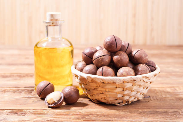 istock Macadamia Nuts in Wicker Basket with Oil on Old Wooden Background 1957102073