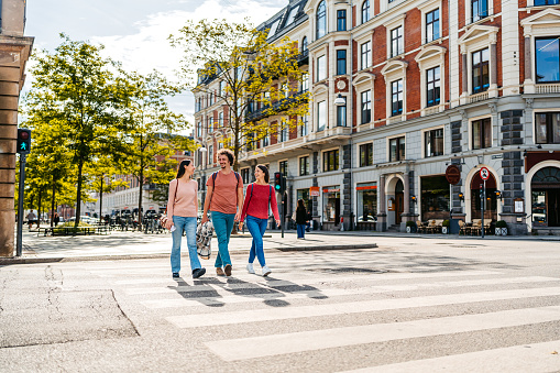 Three young friends crossing the street in Copenhagen in Denmark.