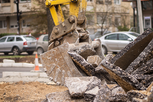 Excavator crushing asphalt on the city street.