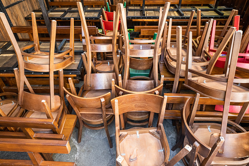 Pile of wooden chairs and tables stacked.