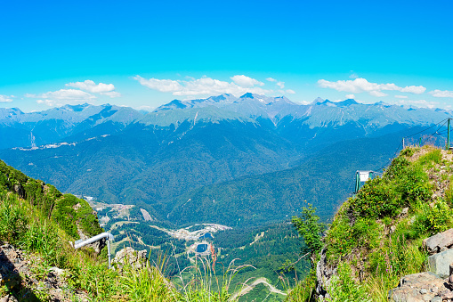 Panorama: view from the Rosa Peak observation deck in Krasnaya Polyana, Sochi, Russia to the Caucasus Mountains in sunny summer weather