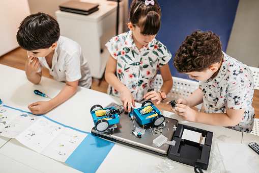 Students In After School Computer Coding Class Building And Learning To Program Robot Vehicle.