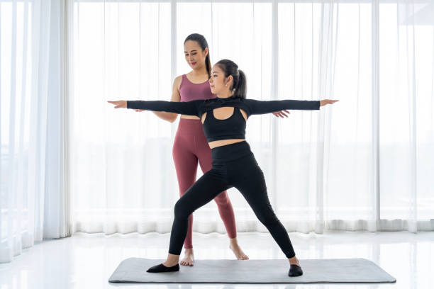 istock Mastering Yoga: Experienced Teacher Guides Student in Perfecting Pose 1957190430