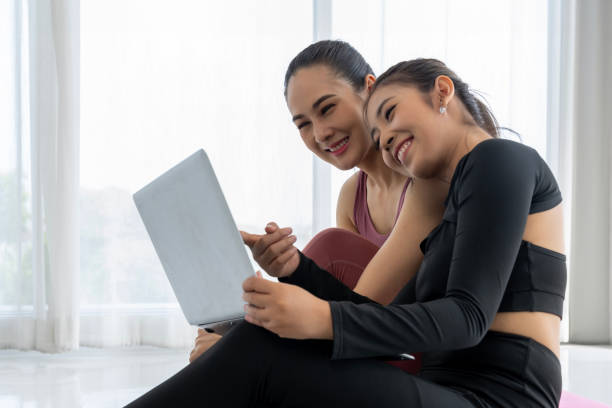 istock Two Asian Women Looking at laptop Together After Workout 1957192129