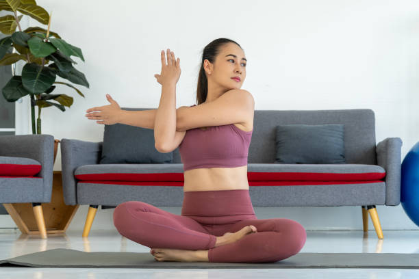 pose de ioga para alongamento de braço: mulher sentada no tapete de yoga - aquecimento físico - fotografias e filmes do acervo