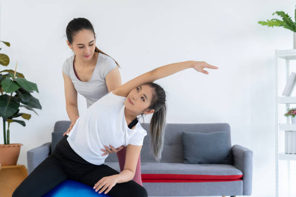 istock Personal trainer assisting client with stretch on fitness ball 1957194905
