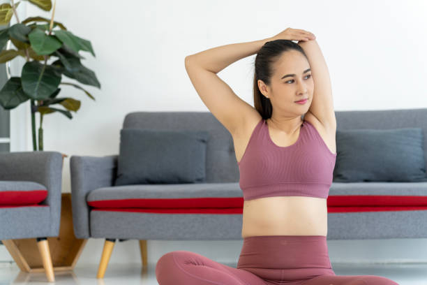 pose de ioga para alongamento de braço: mulher sentada no tapete de yoga - aquecimento físico - fotografias e filmes do acervo
