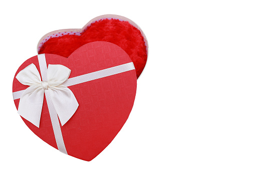 Heart shaped red gift box tied with red ribbon on red background. Horizontal composition with copy space. Directly above. Great use for Christmas and Valentine's Day related gift concepts.
