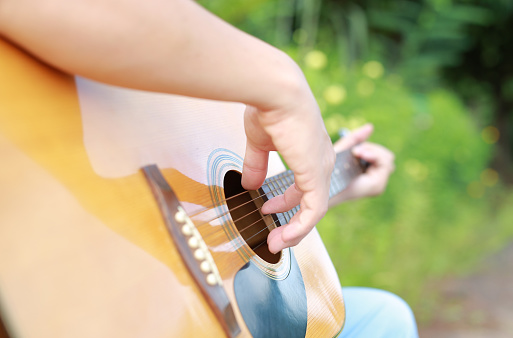 Close-up man playing acoustic guitar outdoor