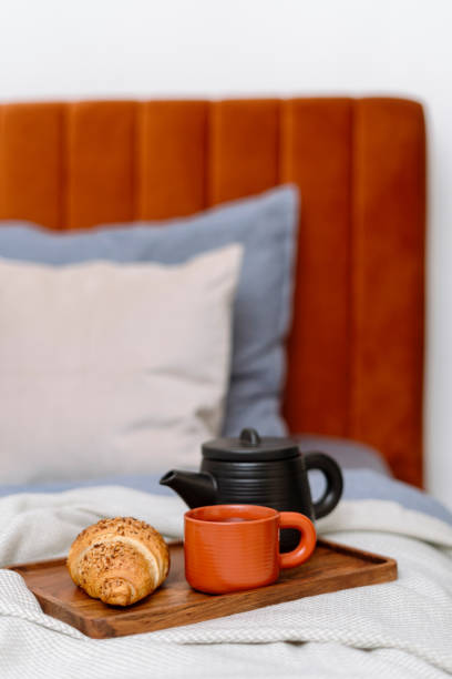istock Selective focus on bamboo tray with teapot, cup and croissant on bed 1957202143