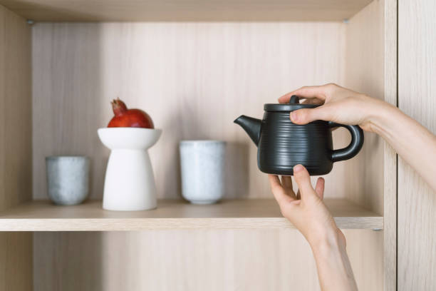 istock Female hands taking ceramic teapot from wooden shelf for prepare tea 1957203204