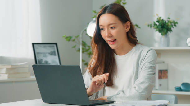 istock Professional young Asian female freelancer or office employee using computer laptop, meeting with co-worker partner team on video call conference and working remotely from home, Confident female manager working at home office 1957207001