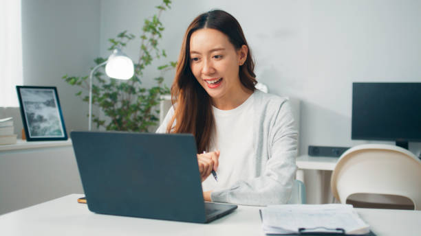 istock Professional young Asian female freelancer or office employee using computer laptop, meeting with co-worker partner team on video call conference and working remotely from home, Confident female manager working at home office 1957209233